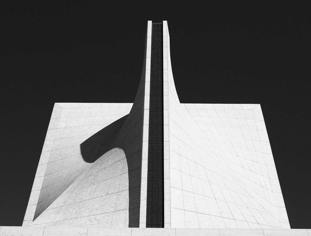 Black and white photograph of a white angular concrete building against a dark sky
